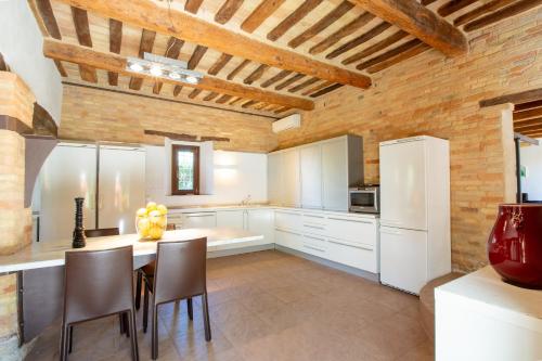 a kitchen with white cabinets and a table and chairs at Casali Marchigiani - Ville vacanza private con piscina in Ostra