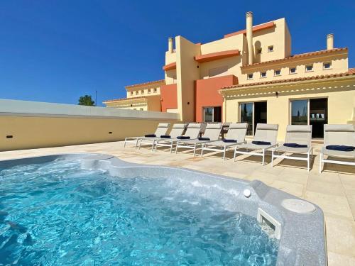a swimming pool in front of a house at Fantastic Villa, Private Pool, BBQ, AC and Wi-Fi in Quarteira