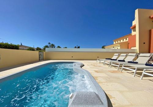 a swimming pool with lounge chairs next to a building at Fantastic Villa, Private Pool, BBQ, AC and Wi-Fi in Quarteira