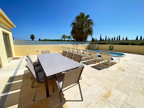 a patio with a table and chairs and a pool at Fantastic Villa, Private Pool, BBQ, AC and Wi-Fi in Quarteira