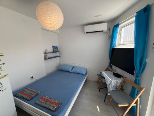 Cette petite chambre comprend un lit bleu et un bureau. dans l'établissement Luna Beach Apartment, à Novalja