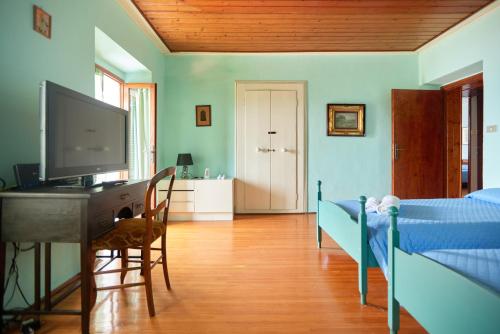 a bedroom with a bed and a desk and a television at Villa di paese - Splendida vista lago Maggiore in Oggebbio