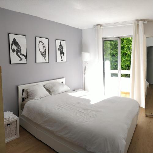 une chambre avec un grand lit blanc et une fenêtre dans l'établissement Chez Gaël, vue mer, piscine, 3chb, à Nice