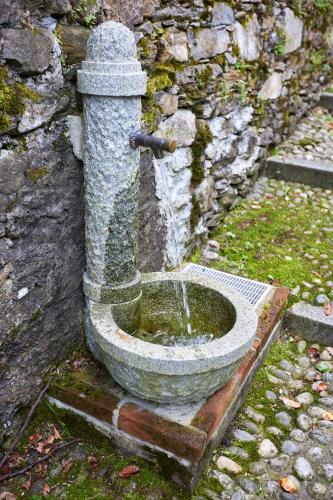 a stone water fountain in front of a stone wall at Villa di paese - Splendida vista lago Maggiore in Oggebbio