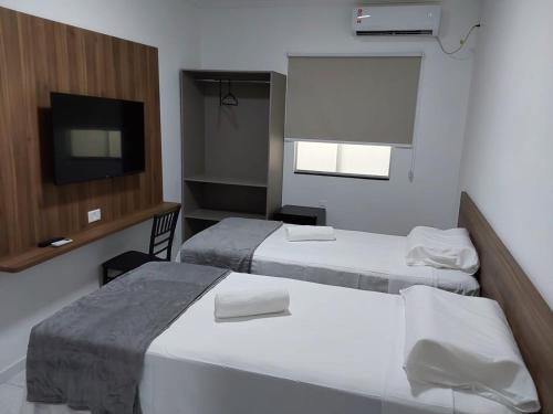 a hotel room with two beds and a flat screen tv at PARALELO 9s HOTEL in Petrolina