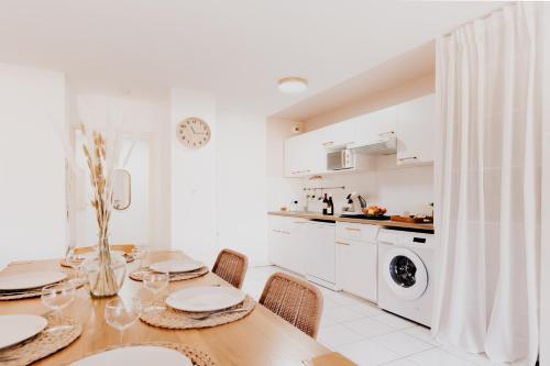a white kitchen with a dining room table with chairs at Le Cocon de Lespinasse - Parking - Checkin Autonome in Lespinasse