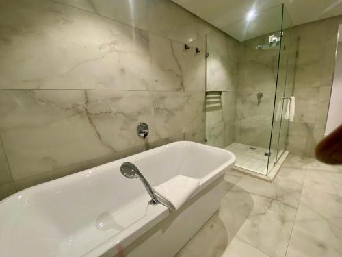 a white bathroom with a tub and a shower at Coastlands Skye Hotel, Ridgeside, Umhlanga in Durban