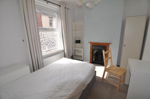a bedroom with a bed and a chair and a fireplace at Exeter Quay & City Centre St Leonards in Exeter