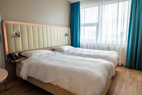 two beds in a hotel room with a window at Park Inn by Radisson Reykjavik Keflavík Airport in Keflavík