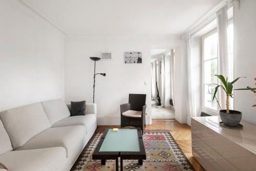 un salon blanc avec un canapé et une table dans l'établissement GuestReady - Séjour Chic au Cœur de Paris, à Paris