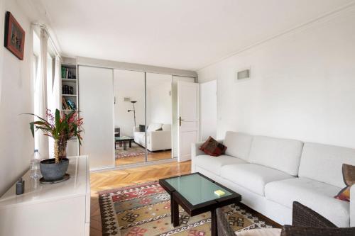 un salon avec un canapé blanc et une table dans l'établissement GuestReady - Séjour Chic au Cœur de Paris, à Paris