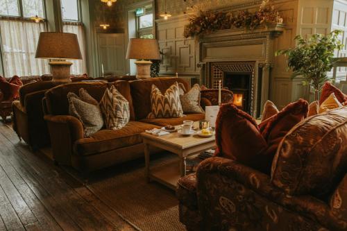 a living room with couches and a table and a fireplace at The William Cecil in Stamford