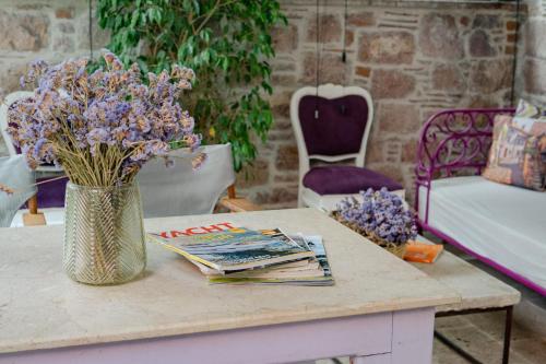 a table with a vase of purple flowers and magazines at cunda mor limon otel in Ayvalık