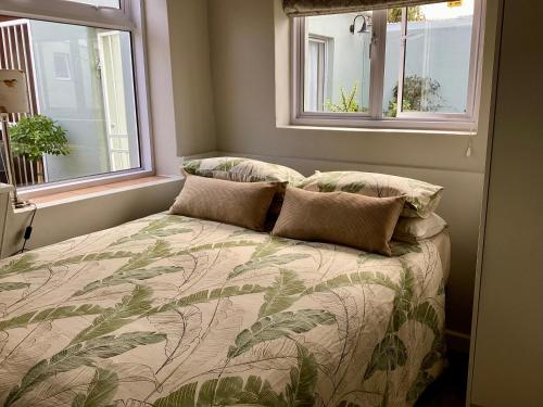 a bedroom with a bed with pillows and two windows at Sage Cottage in Somerset West