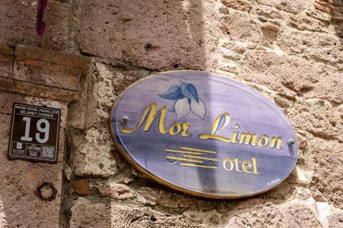 a sign on the side of a stone wall at cunda mor limon otel in Ayvalık