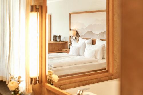 a bedroom with a bed and a mirror at Hotel Auf der Gsteig GmbH in Lechbruck