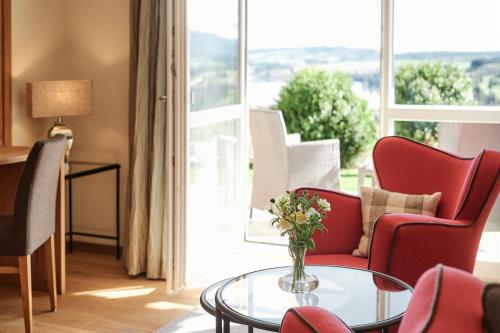 a living room with a table and chairs and a window at Hotel Auf der Gsteig GmbH in Lechbruck