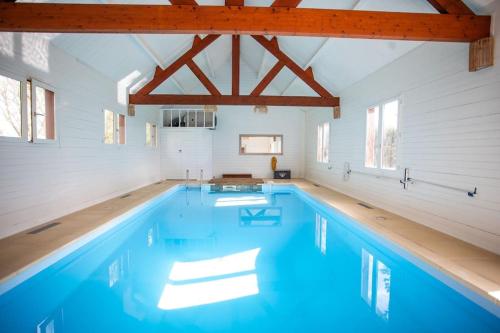 une piscine dans une maison aux murs blancs et à l'eau bleue dans l'établissement La Longère avec Piscine, à Saint-Martin-le-Gaillard