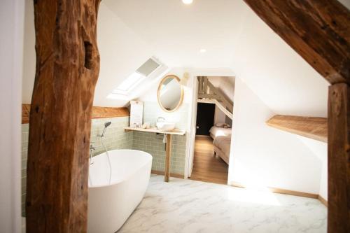 ein Badezimmer mit einer weißen Badewanne und einem Waschbecken in der Unterkunft La Longère avec Piscine in Saint-Martin-le-Gaillard