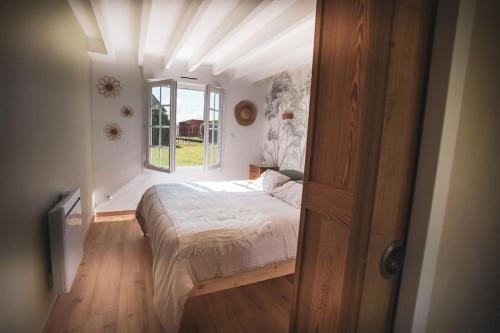 ein Schlafzimmer mit einem Bett in einem Zimmer mit Fenster in der Unterkunft La Longère avec Piscine in Saint-Martin-le-Gaillard