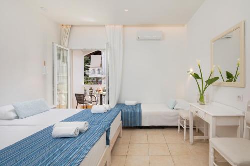 a hotel room with two beds and a desk at Bella Vista Beach Hotel in Benitses