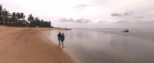 two people standing on a beach near the water at Repousante Beach House in Morrumbene