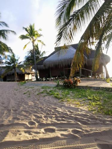 a beach with palm trees and a building at Repousante Beach House in Morrumbene