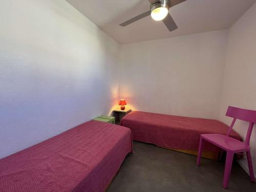 Cette chambre comprend deux lits, une chaise et une lampe. dans l'établissement Maison 4 pièces avec piscine, parking, et lave-vaisselle à Gruissan - FR-1-229-112, à Gruissan