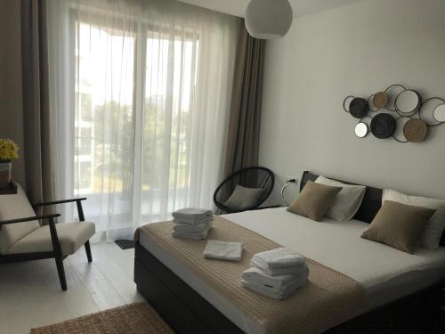 a bedroom with a bed and a chair and a window at Ammos Apartment Mamaia in Mamaia