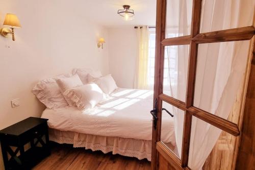 a bedroom with a bed with white sheets and a window at Grande Maison au pied du Col in Arvieux