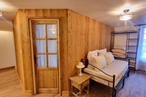 a room with a wooden wall with a bed and a window at Grande Maison au pied du Col in Arvieux
