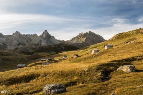 a group of houses on a hill with mountains in the background at Grande Maison au pied du Col in Arvieux