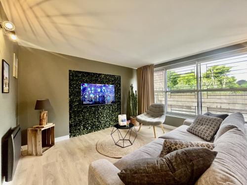 un salon avec un canapé et une télévision dans l'établissement Le Ciel étoilé, à Calais