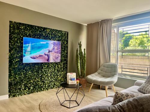 un salon avec un canapé et une télévision sur un mur dans l'établissement Le Ciel étoilé, à Calais