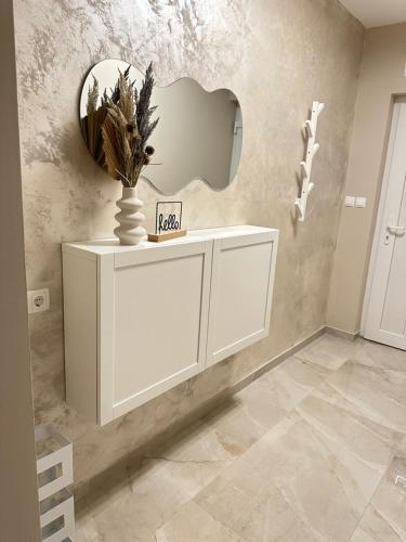 a white cabinet with a mirror and a vase on it at Apartment Forest in Otočac