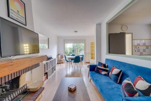 un salon avec un canapé bleu et une télévision à écran plat dans l'établissement Maison de charme à Bacalan avec Terrasse, à Bordeaux