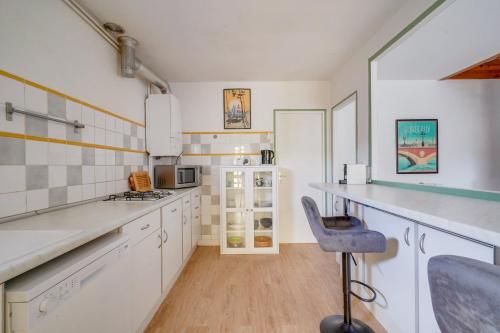 une cuisine avec des placards blancs et une chaise bleue dans l'établissement Maison de charme à Bacalan avec Terrasse, à Bordeaux