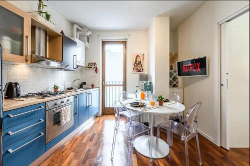 une cuisine avec des armoires bleues et une table et des chaises dans l'établissement Casa Albertina [Grazioso appartamento vicino alla Stazione], à Monza