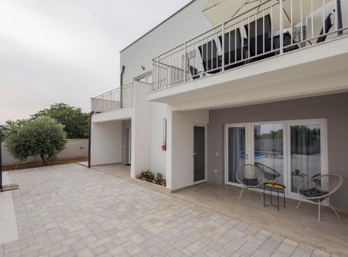 a house with two chairs and a balcony at Holiday Home Milutin 1 in Vrsi