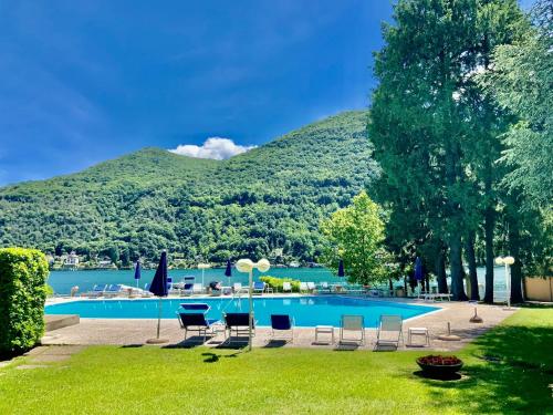 a swimming pool with chairs and a mountain in the background at Casa Giò in Brusimpiano