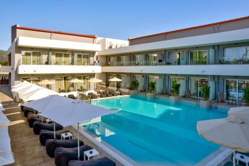 a hotel swimming pool with umbrellas and chairs at White Olive Premium Laganas in Laganas