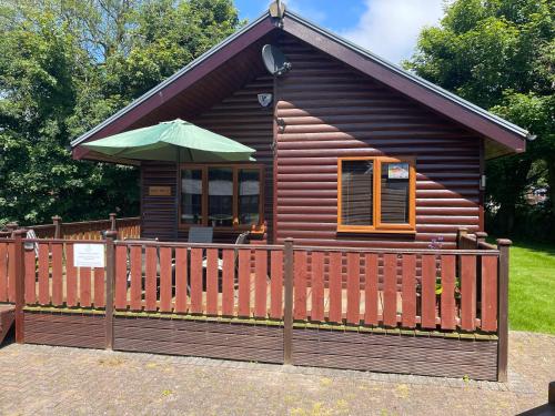 a small cabin with a fence and an umbrella at Nelly's Nest in Bridlington