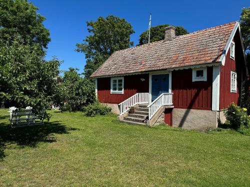 a red barn with a blue door and a yard at Kackelstugan in Borgholm