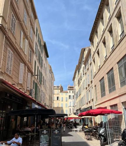 une rue de la ville avec des tables, des parasols et des bâtiments dans l'établissement La Lumineuse - 5 min du Vieux Port Rue Piétonne - Les Frères de la Loc', à Marseille