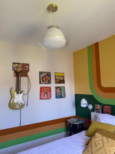 - une chambre avec un lit et une guitare sur le mur dans l'établissement Inspiration maison entière avec jardin, à Pernes-les-Fontaines