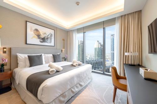 a bedroom with a large bed with a desk and a large window at Address Opera Residences Burj Khalifa View in Dubai