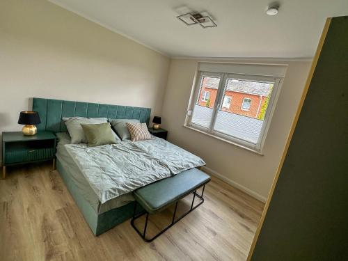 KarstädtにあるFerienhaus Wegblüteのベッドルーム1室(青いヘッドボード付きのベッド1台、窓付)