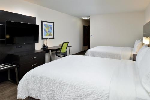 a hotel room with two beds and a flat screen tv at Holiday Inn Express Hotel & Suites Carthage by IHG in Carthage