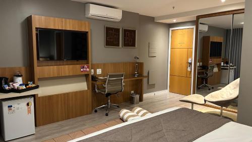 a bedroom with a bed and a desk and a television at Jade Hotel Brasília in Brasilia