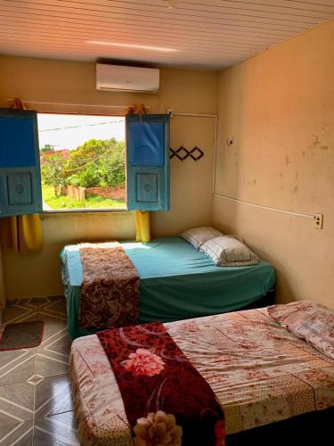 two beds in a room with a window and two bedsitures at Pousada Dois Irmãos in Barreirinhas